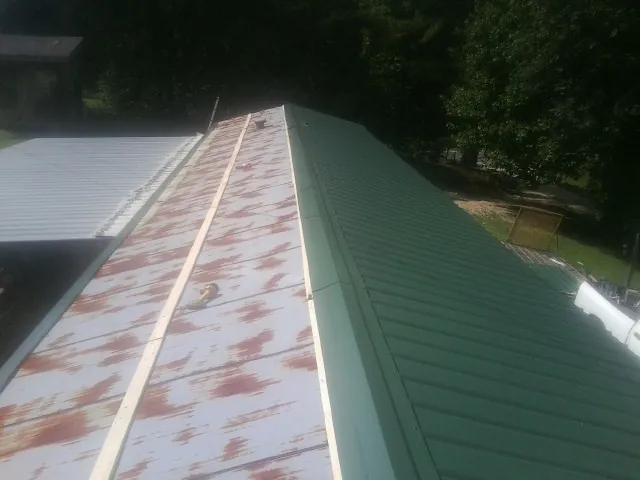 Old rusted panels beside newly installed green metal roofing — Wind Damage Roof Repair by Roofing Brothers in Carey