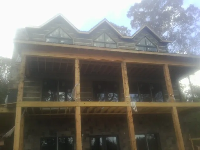 Dormers and porch framing on a large log home under construction — Roof Coating work by our crew in Carey